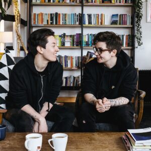 Charlotte and Fionn looking at each other over cups of coffee in a bookshop