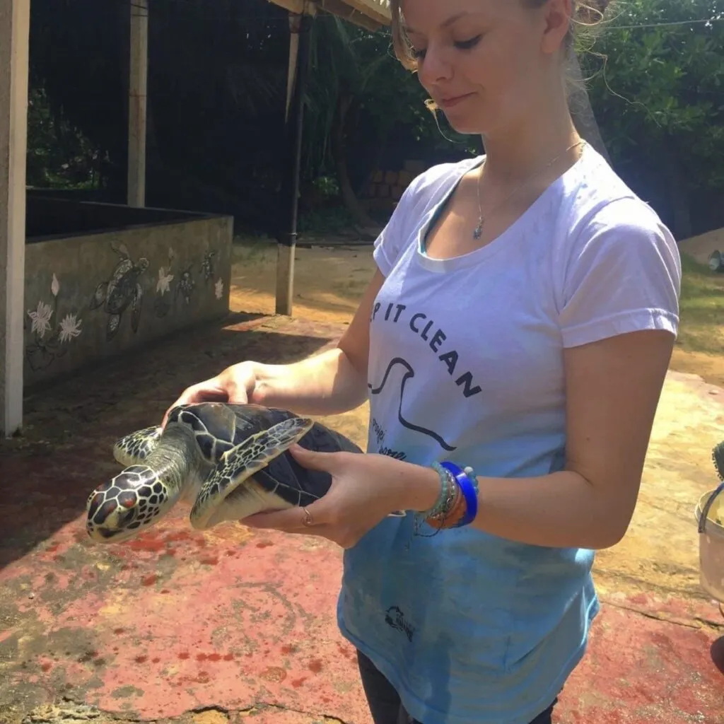 Caitlin Turner holding a turtle, wearing a t-shirt that says 'keep it clean'