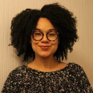 Francesca Sobande smiling at the camera, she is wearing glasses