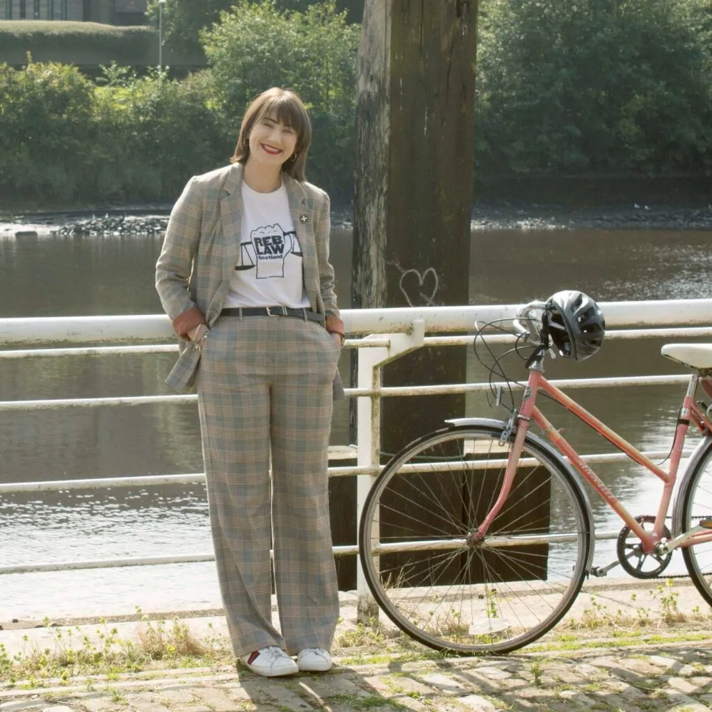 Seonaid Stevenson leaning against a railing beside a canal, with a bike beside her