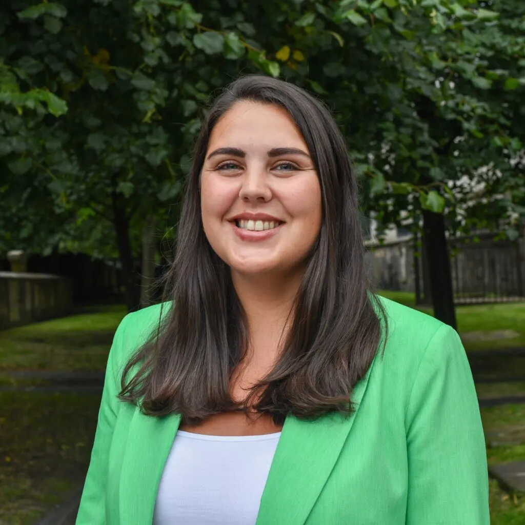 A phot of Jenni Smell smiling at the camera, wearing a green blazer