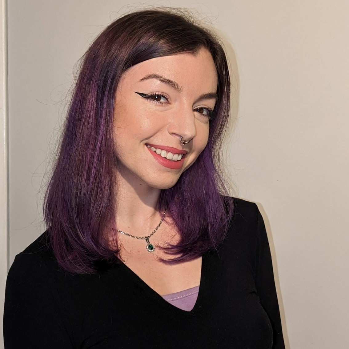 Alanis McQuillen smiling at the camera in front of a plain wall.