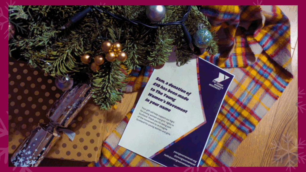 A gift certificate is underneath a christmas tree.