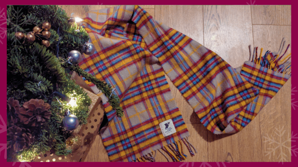 A scarf is underneath the Christmas tree - it's yellow, blue and pink tartan.