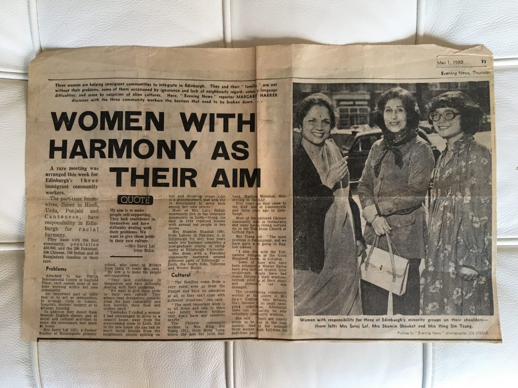 A picture of a newspaper with an image of women standing and smiling and big bold letters title that says 
