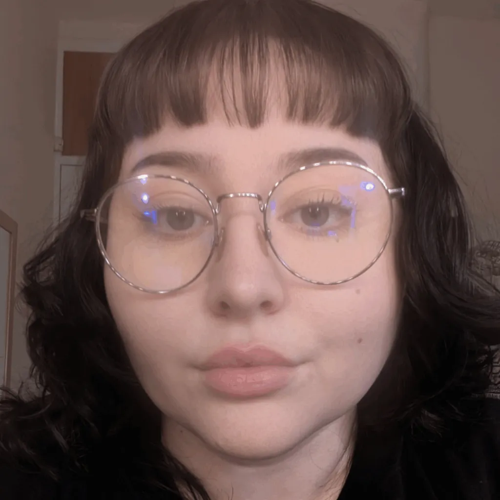Estelle looking at the camera, wearing silver-framed glasses