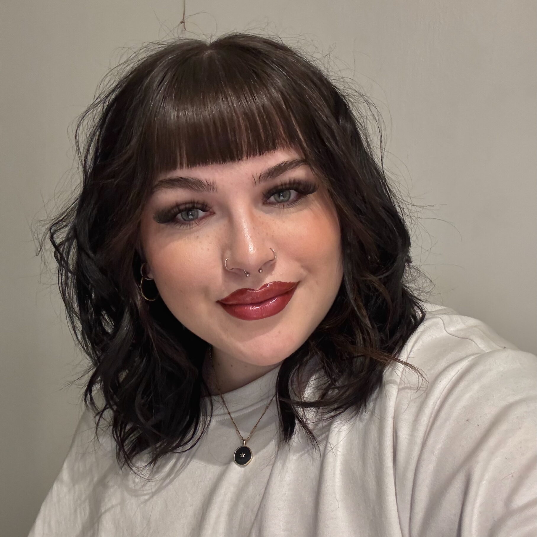 Beth has dark hair with a fringe, and pale skin.