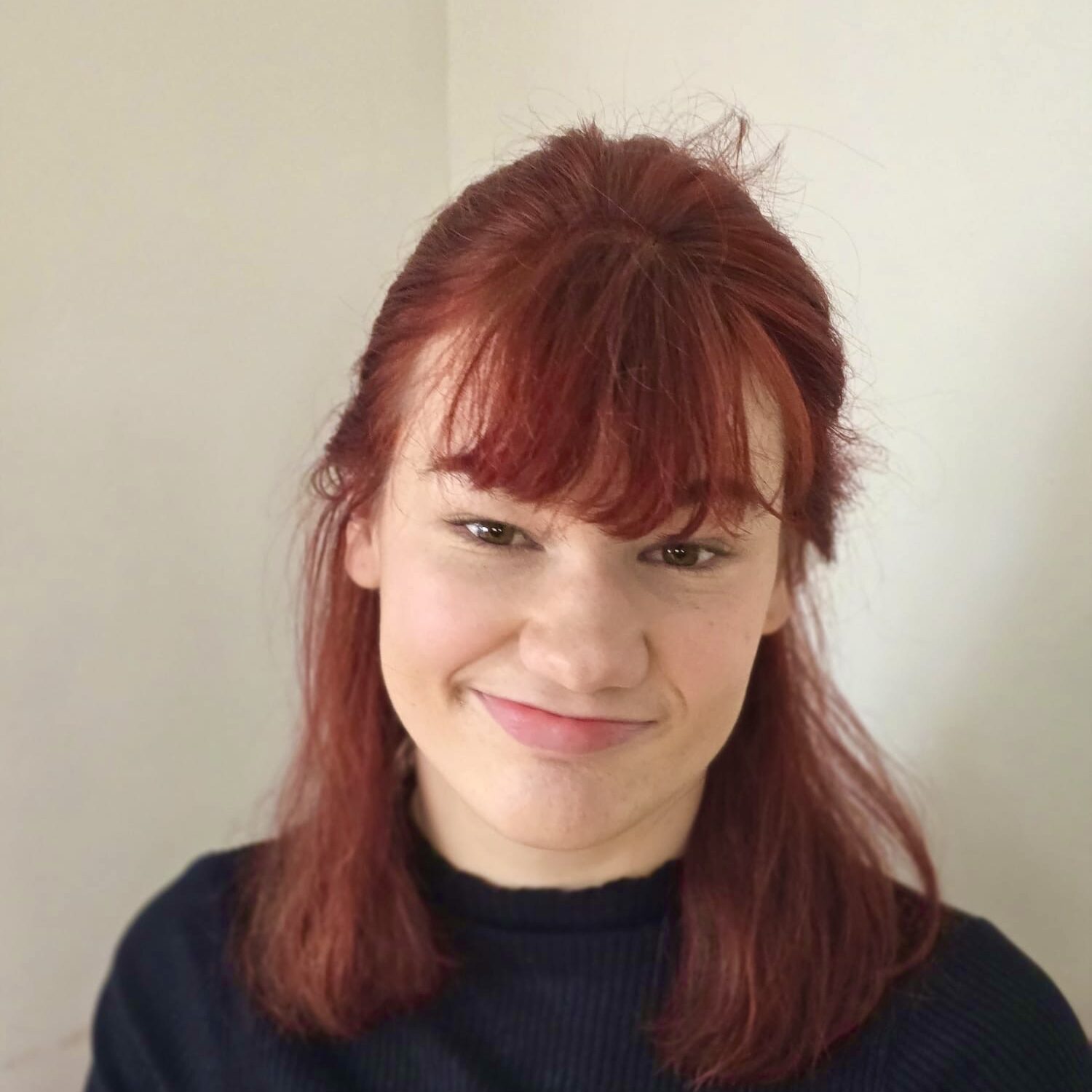 Melissa has pale skin and red hair with a fringe.