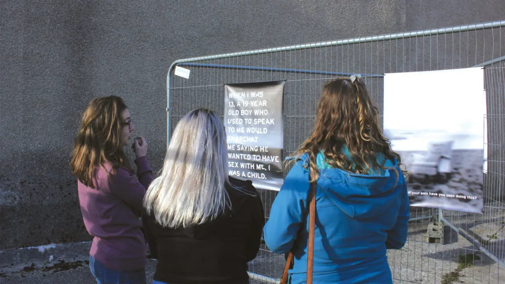 Three women standing in front of a poster that reads 