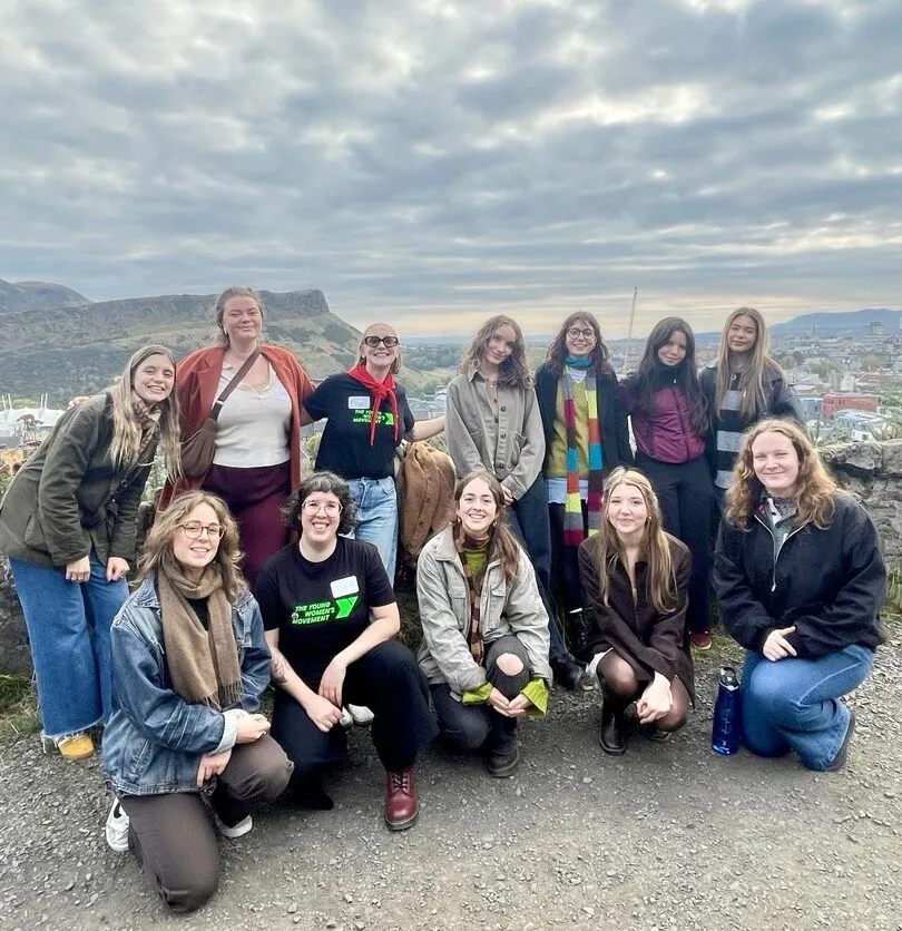 The Young Women Demand group posing with Arthur's seat behind them.