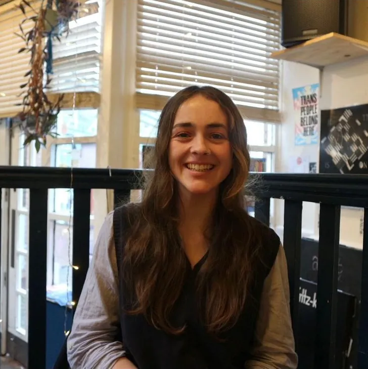 Laura has pale skin and long dark hair. She is smiling at the camera.